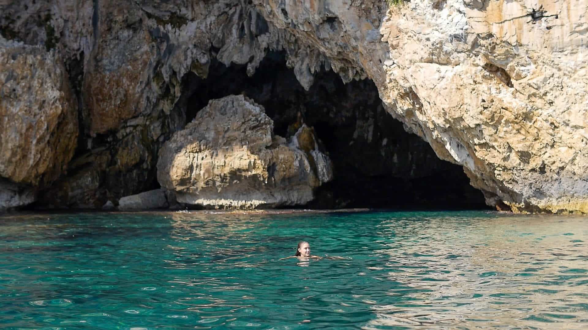 A woman swimmng in front of the sea ​​cave of Panagia Megalomata, during the boat trip “Mamma Mia” provided by the tour agency Pelion Scout.